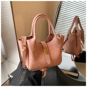 Détail du sac seau rose poudré avec fermoir rotatif doré et texture cuir grainé