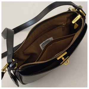 Top view of black crossbody bag with brown lining, golden zipper and spacious compartments