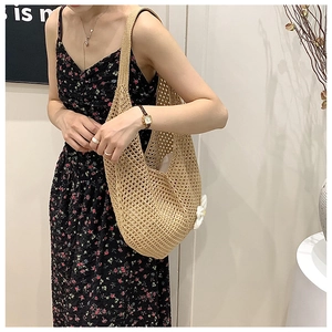Detail of woven hollow tote bag with a white 3D flower charm on the side strap