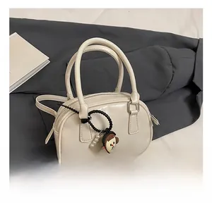 Detail of cream white mini boston bag with shoulder strap and pearl charm accessory