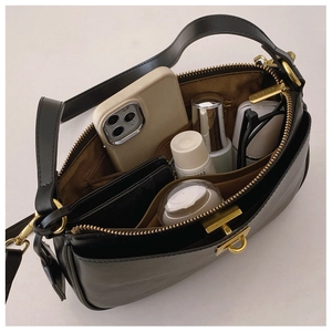 Interior detail of black leather crossbody bag showing spacious compartments and items