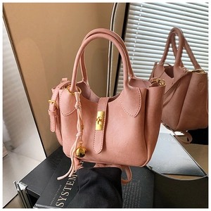 Vue détaillée du sac seau rose en cuir avec fermoir doré et pendentif pompon tressé