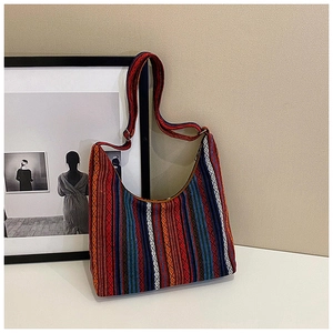 Detalle de bolso tote de punto bohemio con motivos de arcoíris sobre una pared minimalista