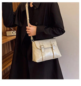 Vue détaillée d'un sac à bandoulière en cuir crème avec boucles argentées sur un modèle