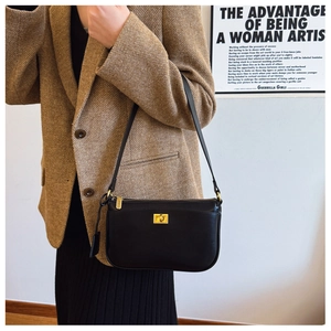 Detail of minimalist black leather crossbody bag with elegant gold metal twist lock