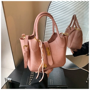 Détail du sac seau rose avec fermoir doré, nœud décoratif et reflet dans le miroir