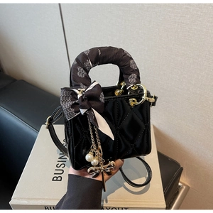 Detail of black patent leather quilted mini handbag with heart silk scarf and pearls