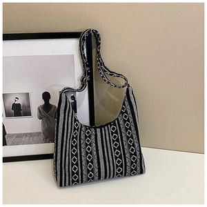 Detalle del bolso hobo con patrones geométricos de rombos y rayas tejidas en blanco y negro