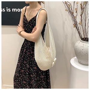 Detail of hand-woven cream tote bag with floral charm and hollow crochet pattern