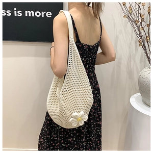 Detail of hand-crocheted beige shoulder bag with hollow mesh and 3D daisy flower charm
