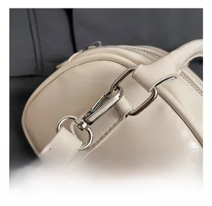 Detailed macro view of silver metallic swivel hook and strap stitching on cream bowling bag