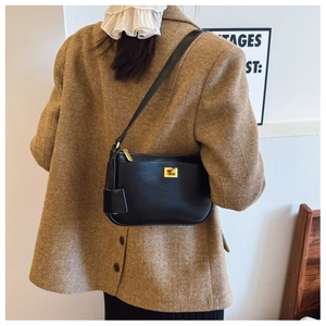 Classic black leather crossbody bag with golden buckle shown on a female model