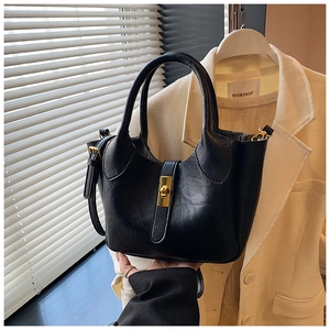Vue détaillée du sac seau noir en cuir texturé avec un fermoir métallique doré poli