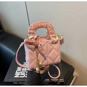 Detail of pink heart-quilted handbag with silk scarf handle and pearl bow charm