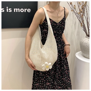 Close-up of cream woven crochet shoulder bag featuring a large white 3D daisy flower detail