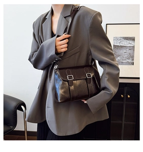 Sacoche rétro chic en finition noire brillante portée avec un blazer gris oversize