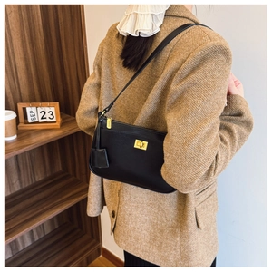 Close-up of black leather shoulder bag featuring elegant gold twist lock and zip closure
