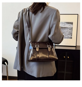 Détail d'un sac à bandoulière vintage en cuir marron foncé avec fermeture à double boucle