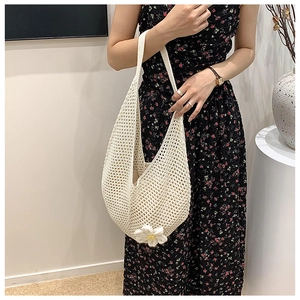 Detailed shot of a woven tote bag featuring a delicate handcrafted daisy flower accent