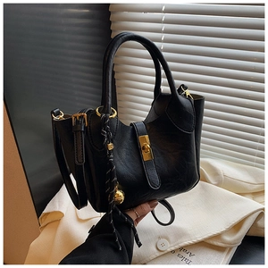Détail du sac seau noir avec fermoir doré et pendentif décoratif en corde tressée