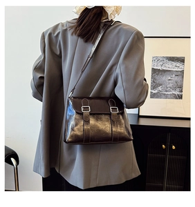 Détails d'un sac bandoulière vintage en cuir marron brillant à boucles argent
