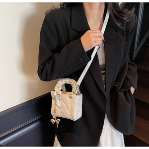 Mini quilted white leather bag featuring a silk-wrapped handle and elegant pearl charm