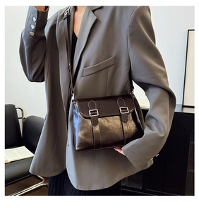 Détail d'un sac messager vintage en cuir huilé brillant avec boucles argentées