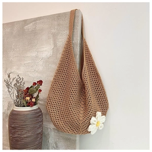 Close-up of woven tote bag featuring a crochet flower detail against a textured wall