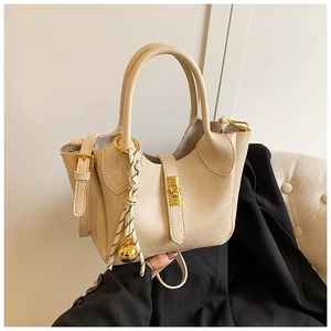 Détail du sac seau crème avec fermoir rotatif doré et pendentif cloche tressé