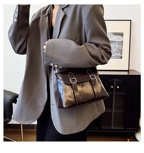 Sac bandoulière marron foncé brillant porté sur un blazer gris pour un look chic moderne