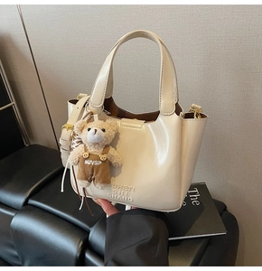 Detailansicht der cremefarbenen Lackleder-Beuteltasche mit süßem Teddybär-Anhänger