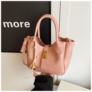Détail du sac seau en simili cuir rose avec fermoir doré et accessoire cloche