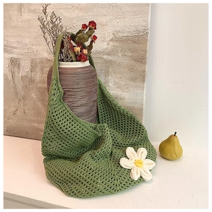 Detail of green crochet tote bag with white knitted flower and mesh hollow texture