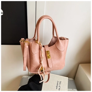 Détail du sac seau rose avec fermoir rotatif doré et breloque décorative en corde