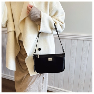 Detail of a matte black leather shoulder bag with silver twist lock on a beige wool coat