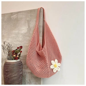 Detail of orange woven tote bag with a white 3D crochet flower on stone wall