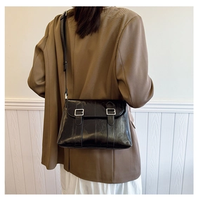 Détail d'un sac bandoulière noir brillant avec double boucle argentée et sangle réglable