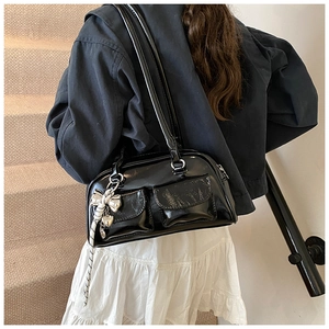 Detalle de un bolso Boston negro brillante con bolsillos dobles y colgante decorativo