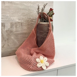 Detail of pink crochet tote bag featuring a white 3D floral accent and woven mesh texture