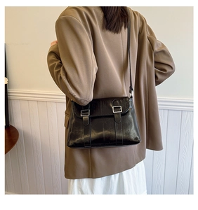 Détail du sac bandoulière noir en similicuir brillant à doubles boucles