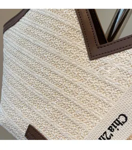 Detailed view of beige woven straw tote with premium brown leather trim and fashion label