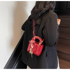 Detail of red quilted mini handbag with decorative silk scarf and pearl charm