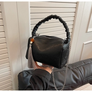 Detail of black ruched handle and embossed texture on a crossbody pillow bag