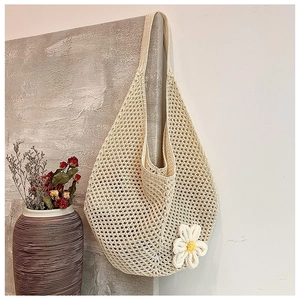 Close-up of beige crochet tote bag with openwork mesh weave and white daisy flower detail