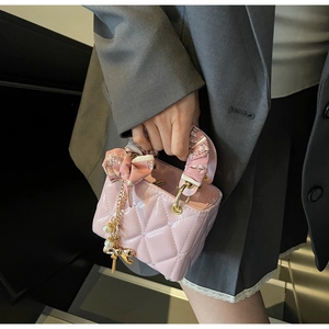 Detailed macro view of pink quilted handbag with silk scarf handle and pearl bow charm