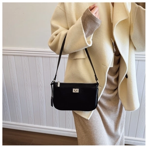 Close-up of a black leather underarm bag with a silver square clasp on a beige coat