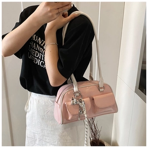 Detalle del bolso de hombro en charol rosa con lazo decorativo y dos bolsillos frontales