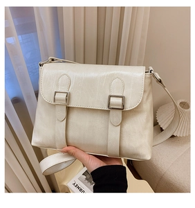 Détail d'un sac à bandoulière en cuir froissé beige avec boucles argentées et rabat