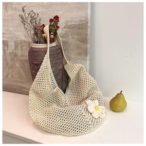 Detail of cream crochet shoulder bag featuring a 3D knit flower and woven texture