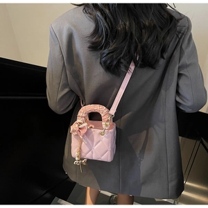 Close-up of pink quilted mini bag with silk scarf handle and pearl butterfly pendant